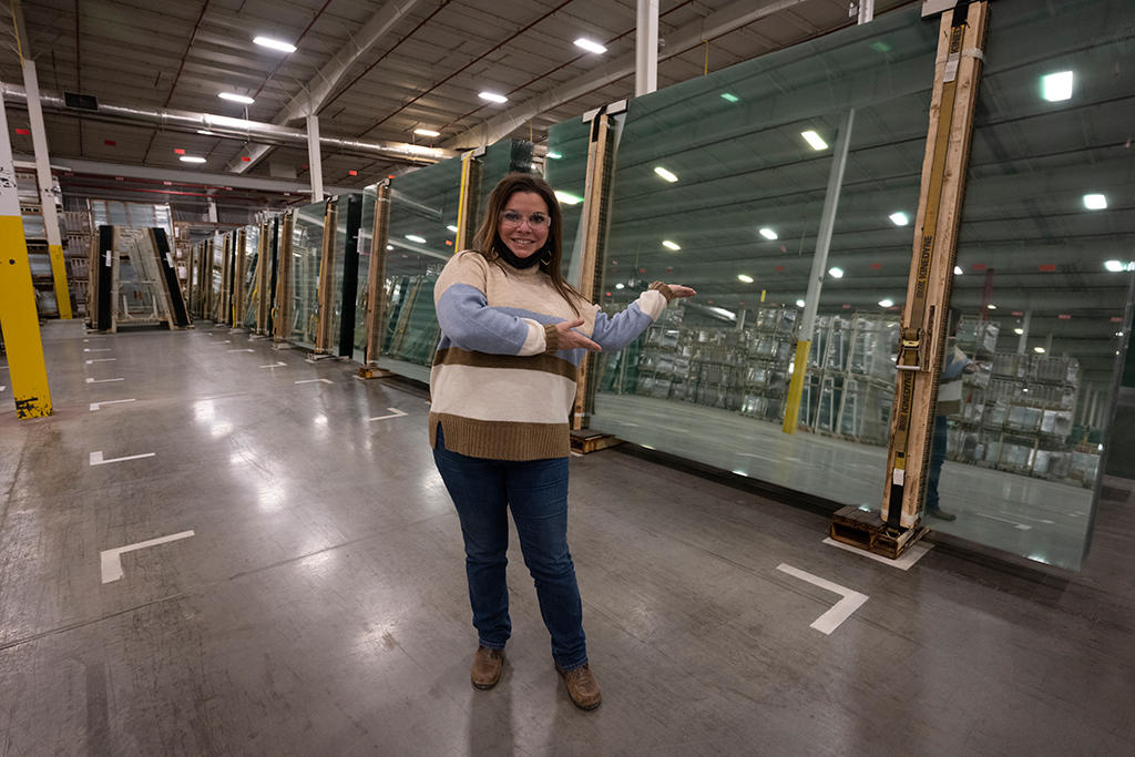 Employee posing in front of sheets of glass